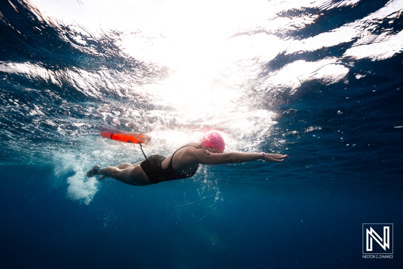 Diver swims underwater in Curacao near the surface with sunlight shining