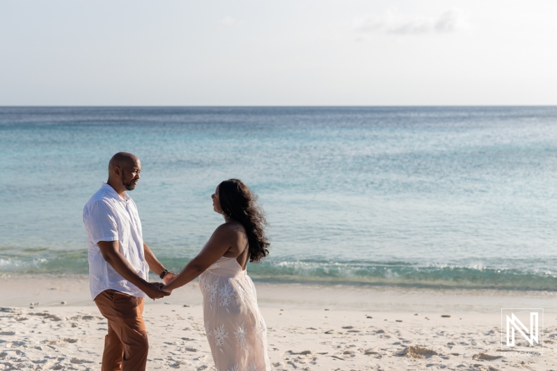 Couple celebrates vow renewal and pregnancy reveal on a picturesque beach in Curacao during golden hour