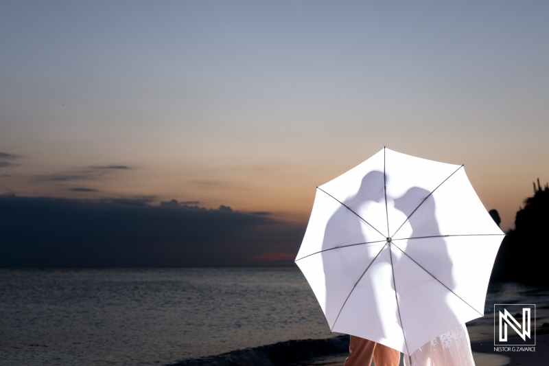 Couple celebrates vow renewal and pregnancy reveal on the beach in Curacao during sunset