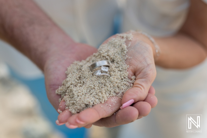 Couple celebrates vow renewal with wedding rings on sandy beach in Curacao under sunny skies