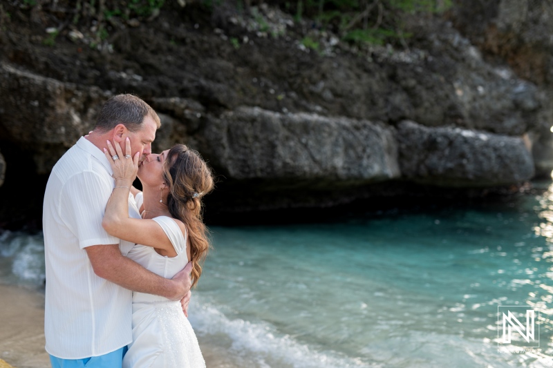 Couple renews their wedding vows on a beautiful beach in Curacao surrounded by serene turquoise waters and natural rock formations