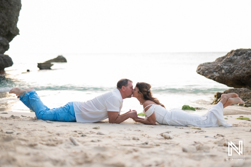Couple celebrates vow renewal on a serene beach in Curacao during golden hour with intimate moment captured at water's edge