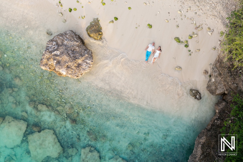Couple celebrates vow renewal on a serene beach in Curacao during a sunny day, surrounded by gentle waves and beautiful scenery