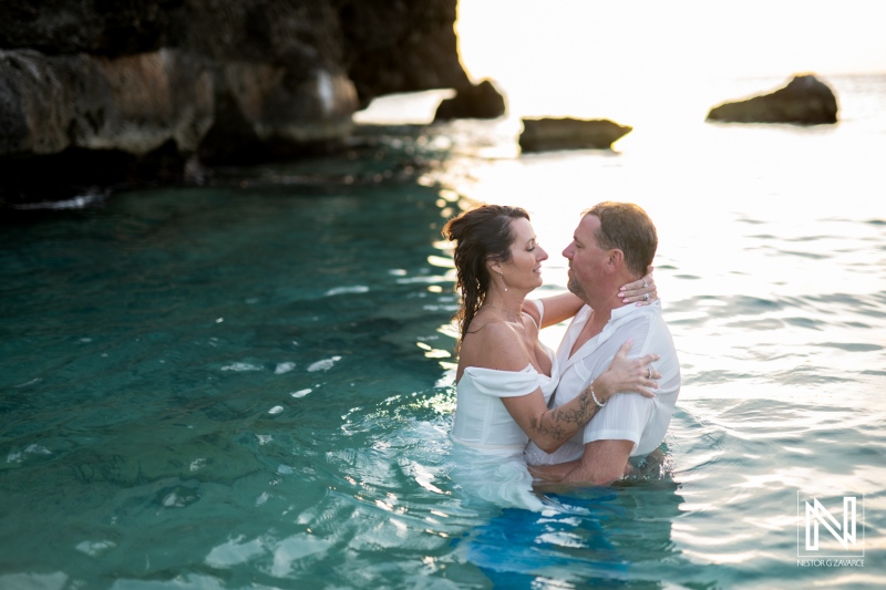Couple celebrates vow renewal in tranquil waters of Curacao as the sun sets on a beautiful evening