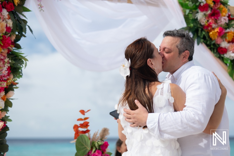 Couple shares a tender kiss during vow renewal ceremony at Cas Abao Beach in Curacao on a sunny day