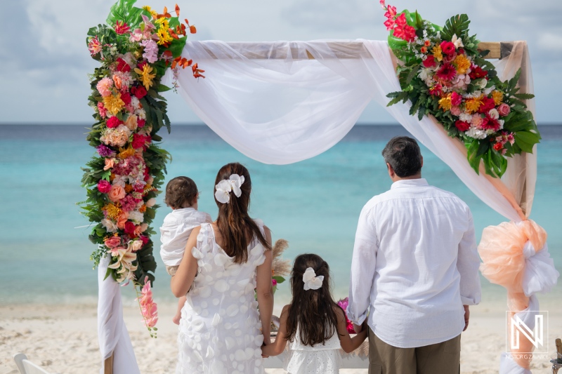 Vow renewal ceremony at Cas Abao Beach in Curacao with family amidst stunning tropical scenery and vibrant floral decorations