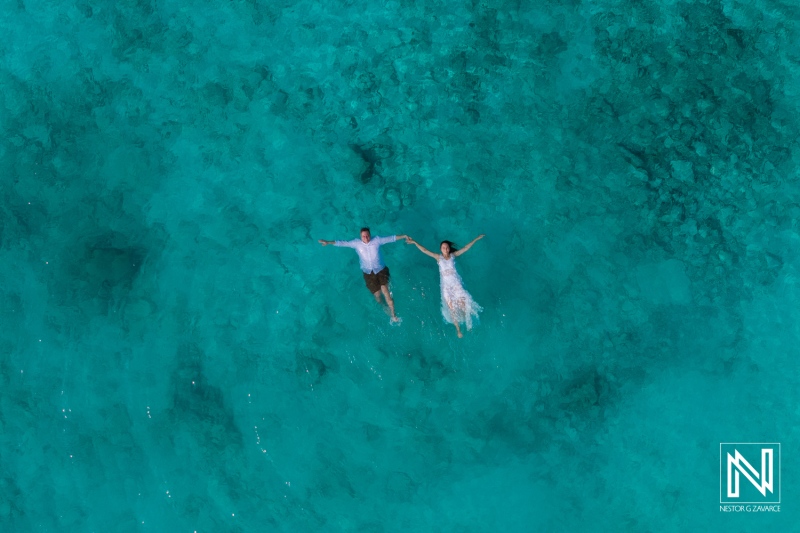 Couple enjoying a romantic vow renewal celebration while floating in the clear waters of Cas Abao Beach, Curacao