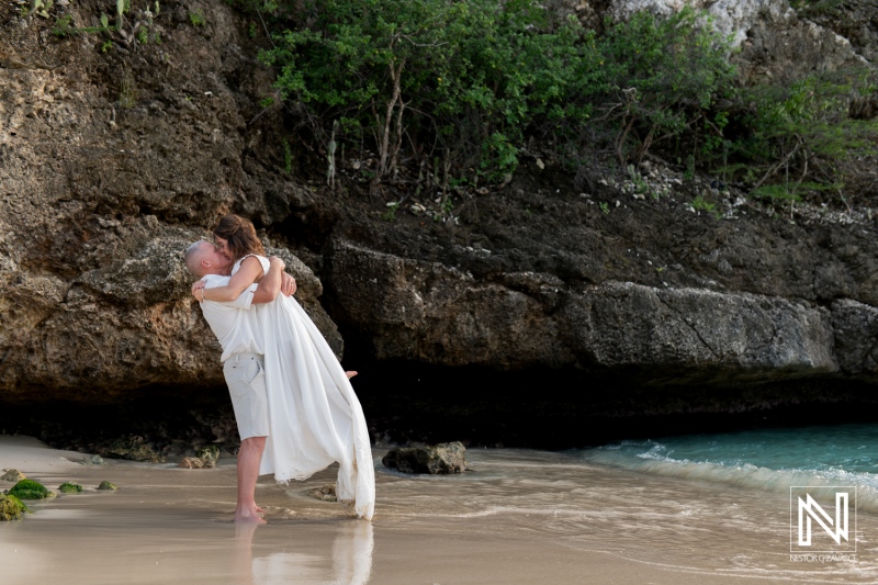Couple rejoices in vow renewal ceremony on Curacao beach with stunning backdrop and sunset glow