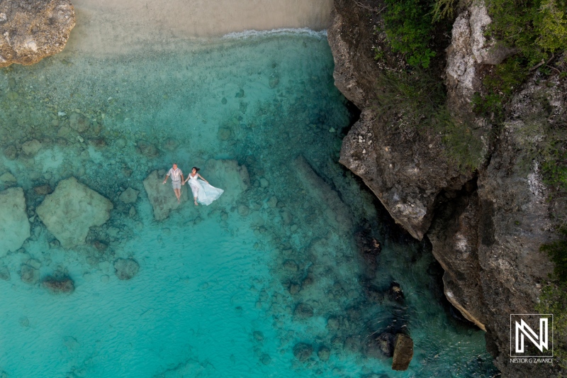 Couple celebrates vow renewal in stunning turquoise waters of Curacao against a backdrop of natural beauty and rocks