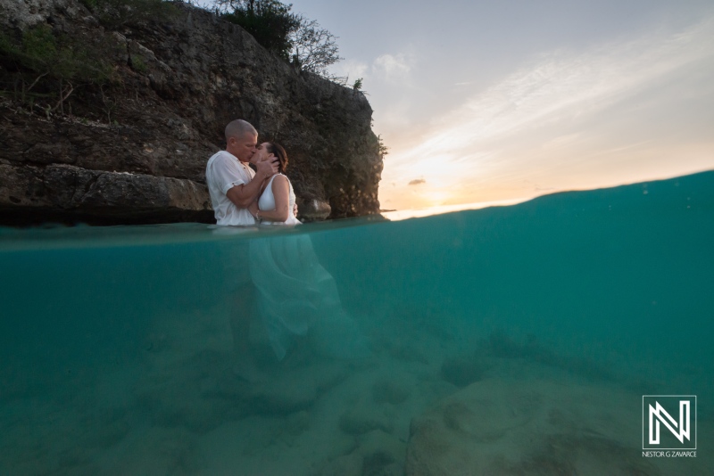 Couple embraces during romantic vow renewal in crystal-clear waters of Curacao at sunset