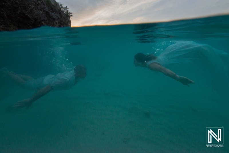 Vow renewal ceremony underwater in Curacao with couple swimming together in clear turquoise water at sunset