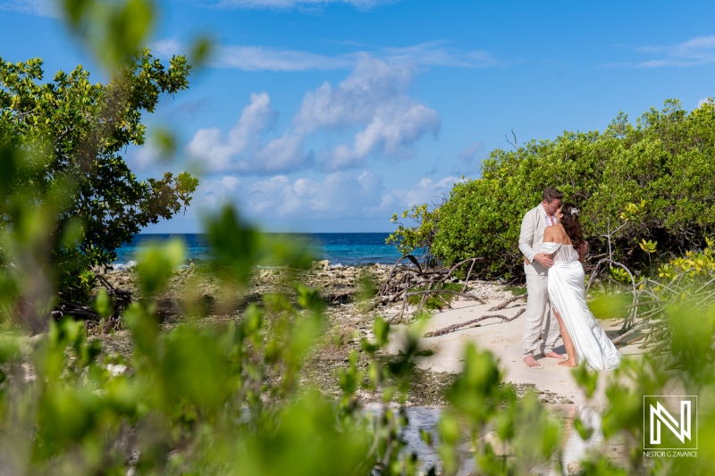 Vow renewal ceremony at Doggy Beach in Curacao under a clear blue sky with lush greenery surrounding the couple