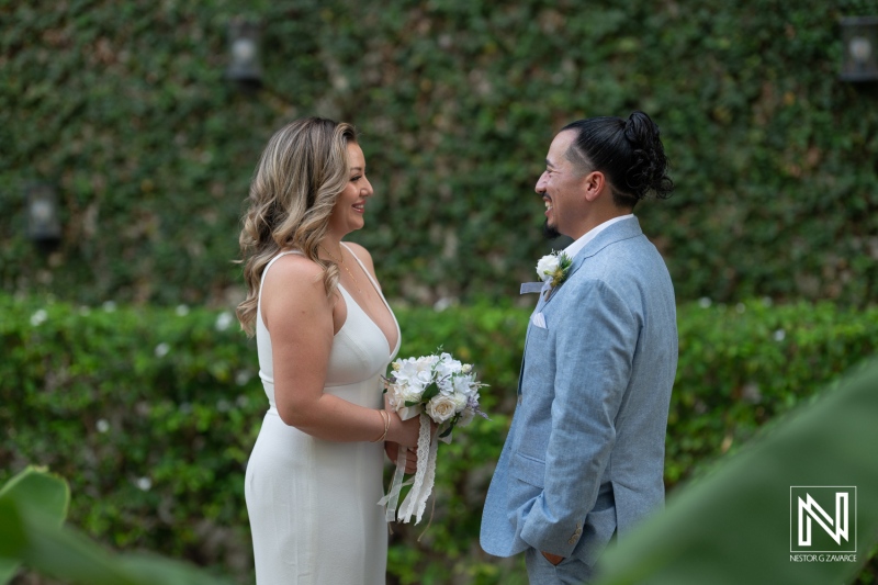 A Joyful Couple Exchanges Vows in an Outdoor Ceremony Surrounded by Lush Greenery and Floral Arrangements During Sunset in a Romantic Setting