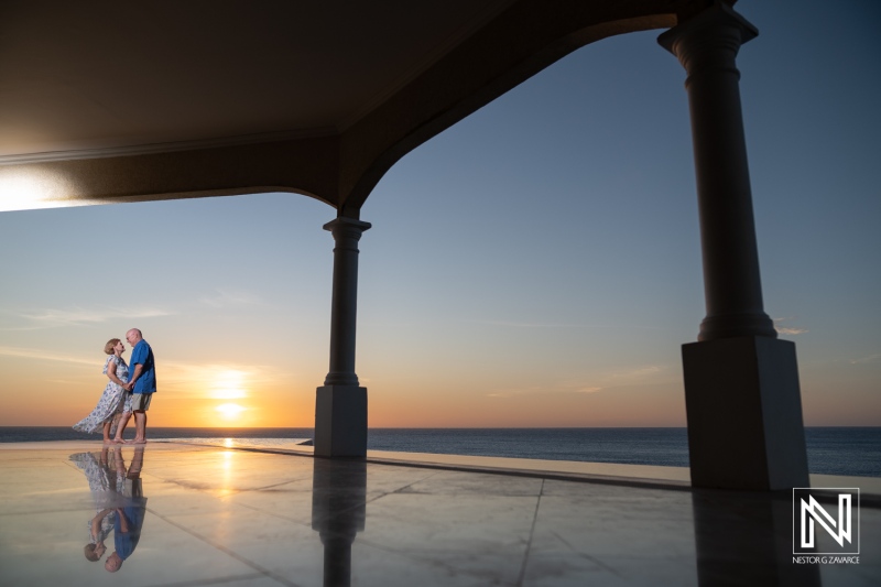 Couple Embraces at Sunset by the Ocean in a Serene Coastal Setting With a Beautiful Sky and Reflections on the Marble Floor