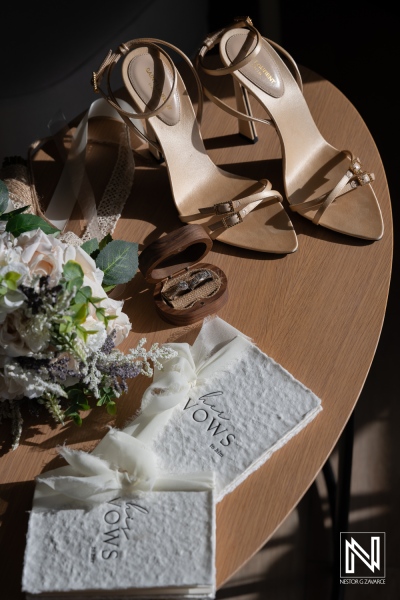 Couples prepare to renew vows with shoes, rings, and vow books on table in Curacao Marriott Beach Resort