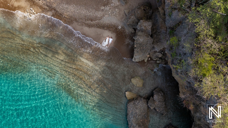 Couple celebrates vow renewal at Playa Jeremi during a sunny day in Curacao with waves gently lapping at the shore