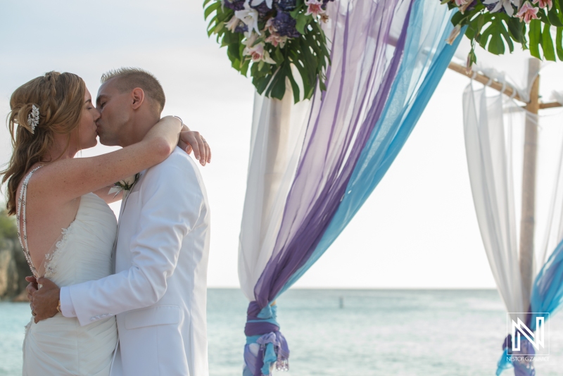 Bride and groom kissing in the beach gazebo
