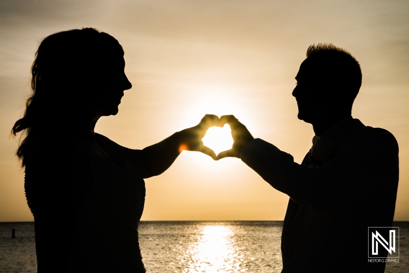 Bride and groom making a heart with a beautiful sunset