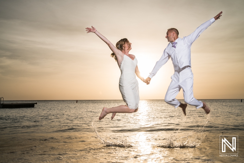 Bride and groom jumping on the beach with a beautiful sunset