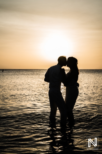Bride and groom kissing on the beach with a beautiful sunset