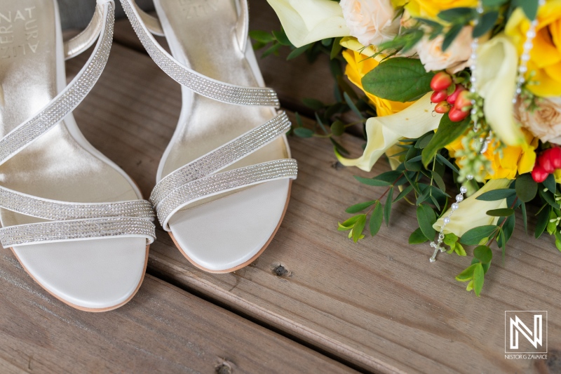 Elegant Silver Sandals Paired With a Vibrant Bouquet on a Wooden Surface, Showcasing Wedding Details in a Natural Setting During Daylight