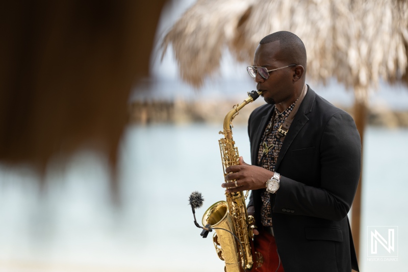 A Musician Plays the Saxophone at a Tropical Beach Resort, Surrounded by Palm Trees and a Relaxing Ocean Backdrop During a Sunny Afternoon