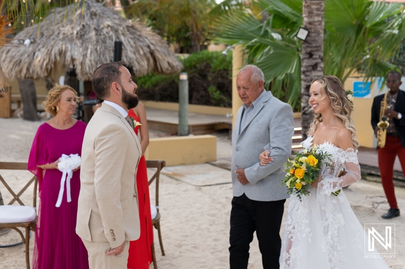 A Couple Exchanges Vows During a Beach Wedding Ceremony Surrounded by Family in a Tropical Setting at Sunset