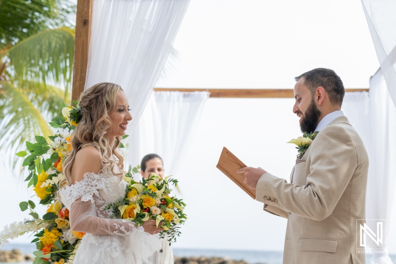 A Beautiful Beach Wedding Ceremony at Sunset With the Bride and Groom Exchanging Vows Surrounded by Floral Decor and an Ocean Backdrop