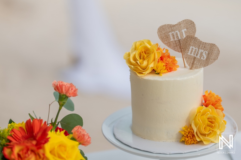 A Beautifully Decorated Wedding Cake With Floral Arrangements Showcasing Vibrant Colors at an Outdoor Ceremony During Sunset on a Picturesque Beach