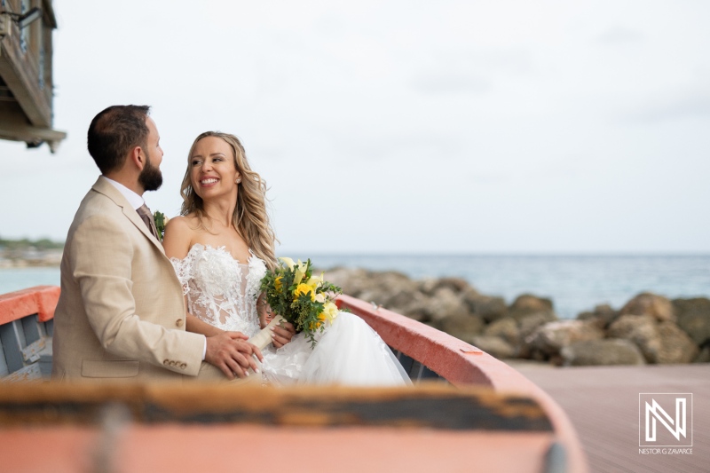 A Joyful Couple Enjoying Their Wedding Celebration on a Boat by the Ocean, Surrounded by Scenic Rocks and a Peaceful Shoreline During a Sunny Day