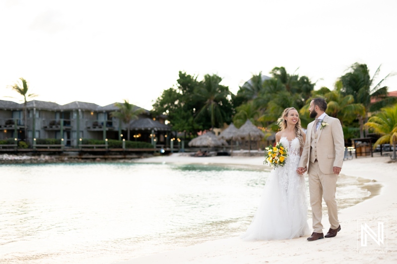 A Joyful Couple Walks Hand-In-Hand Along a Picturesque Beach, Surrounded by Lush Palm Trees and a Serene Ocean During Golden Hour After Their Wedding Ceremony