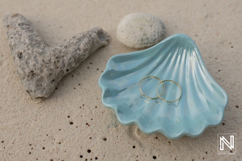 LGBT wedding rings resting on a shell at Cas Abao Beach during sunrise in Curacao celebrating love and unity