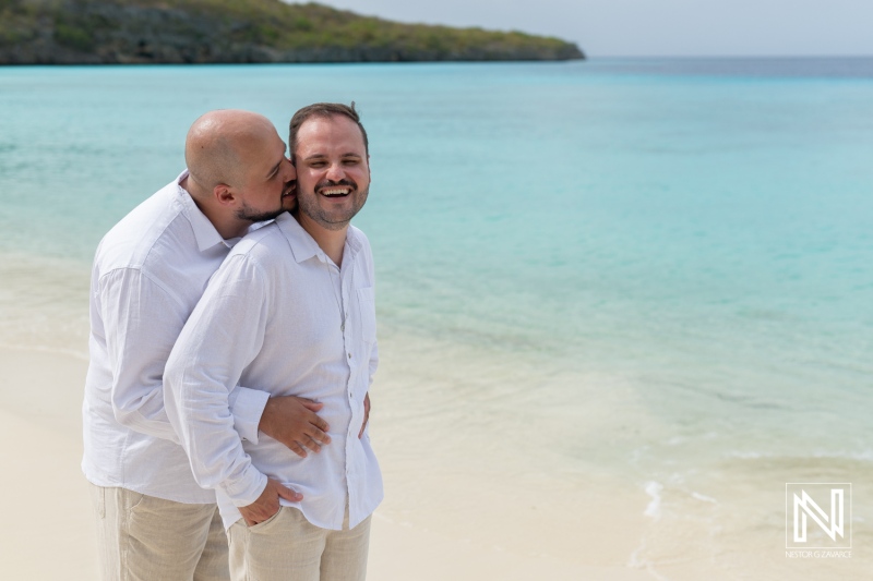 LGBT wedding celebration at Cas Abao Beach in Curacao during sunrise with joyful couple embracing each other near the serene shoreline