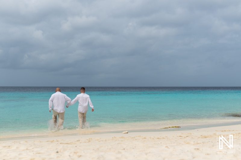 LGBT wedding celebration during sunrise at Cas Abao Beach in Curacao, with two grooms walking hand in hand along the shoreline