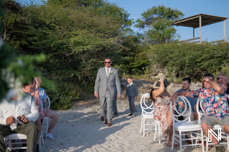 Groom and young boy walk down sandy aisle at Coral Estate Luxury Resort in Curacao for a beautiful wedding ceremony