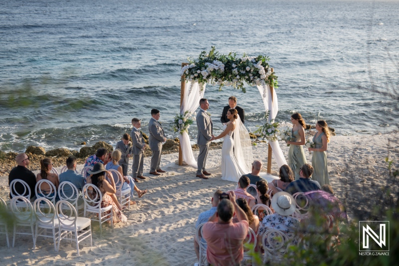 Wedding ceremony at Coral Estate Luxury Resort in Curacao with ocean backdrop and floral arch