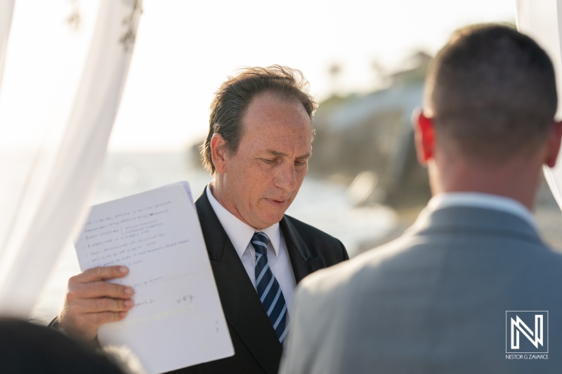 Elegant wedding ceremony at Coral Estate Luxury Resort in Curacao with officiant guiding vows against a stunning ocean backdrop