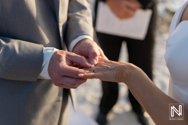 Couple exchanges wedding rings during ceremony at Coral Estate Luxury Resort in Curacao on a sunny day