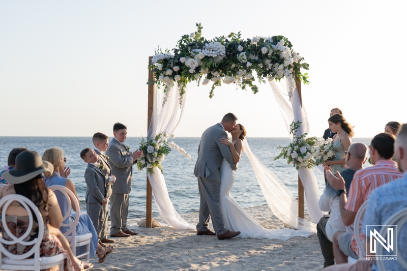 Wedding ceremony on the beach at Coral Estate Luxury Resort in Curacao with sunset backdrop and joyful guests celebrating
