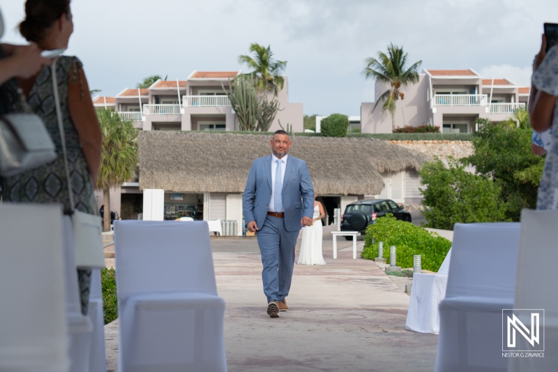 Groom walks down the aisle at a beautiful wedding ceremony in Curacao, surrounded by guests and tropical scenery