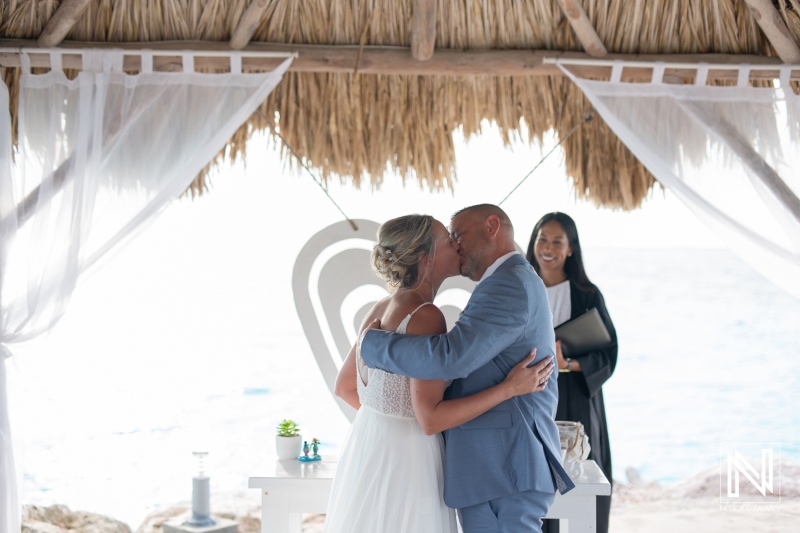 Couple shares passionate kiss during wedding ceremony at Karakter in Curacao with beautiful ocean backdrop