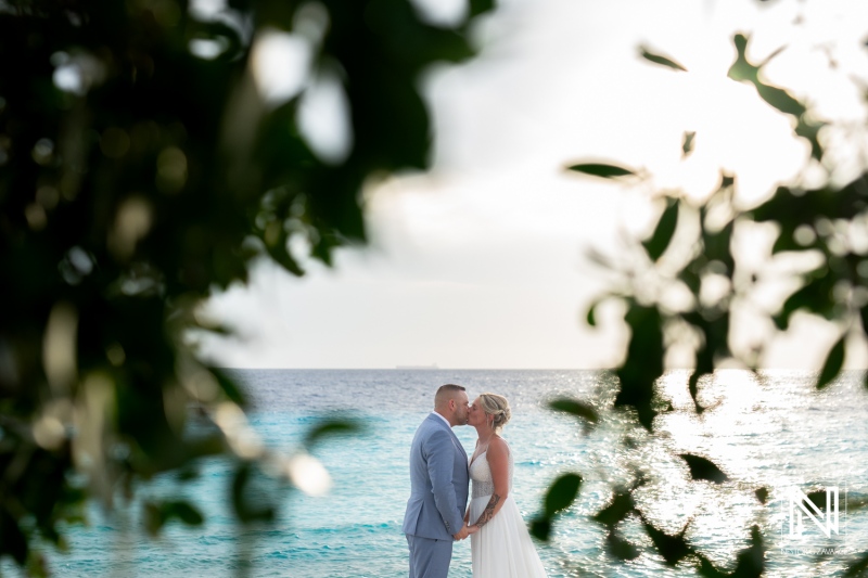 Couple shares a romantic kiss at their wedding on the shores of Curacao during a beautiful sunset