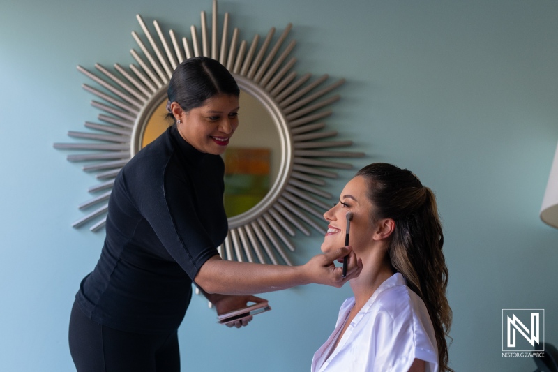 Makeup artist applying cosmetics to a smiling woman in a bright room with a decorative mirror during morning preparations