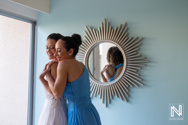 Two women share a joyful embrace in a bright room adorned with a stylish sunburst mirror, capturing the essence of friendship and celebration in a serene atmosphere