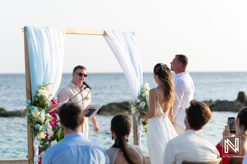 A couple exchanges vows during a picturesque beach wedding ceremony at sunset with guests witnessing the moment in a serene coastal setting