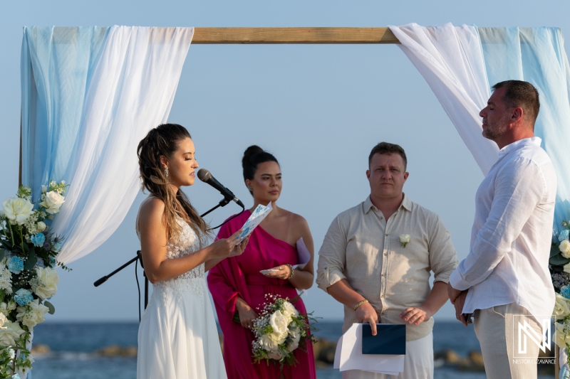 Beach wedding ceremony at sunset with bride, groom, and officiant exchanging vows in a picturesque coastal setting