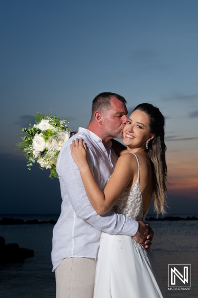 Outdoor wedding celebration during sunset with a happy couple embracing, surrounded by nature and a beautiful bouquet