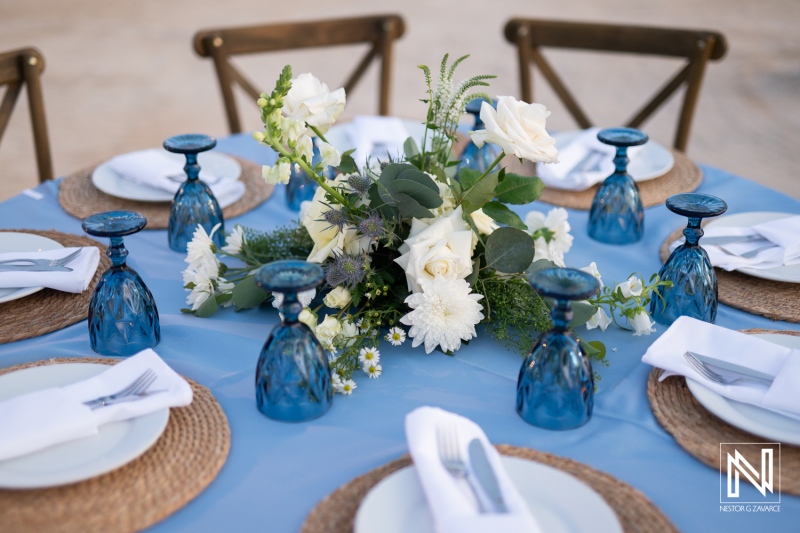 Beautifully arranged dining table with floral centerpiece in blue tones set for an outdoor gathering during a sunny afternoon