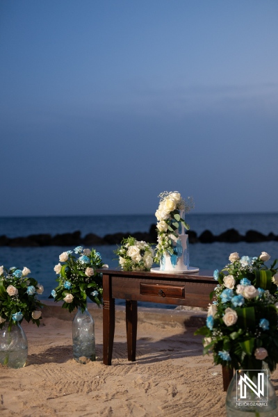 A romantic beach wedding setup featuring elegant floral arrangements and a decorated table at sunset by the ocean in a serene atmosphere