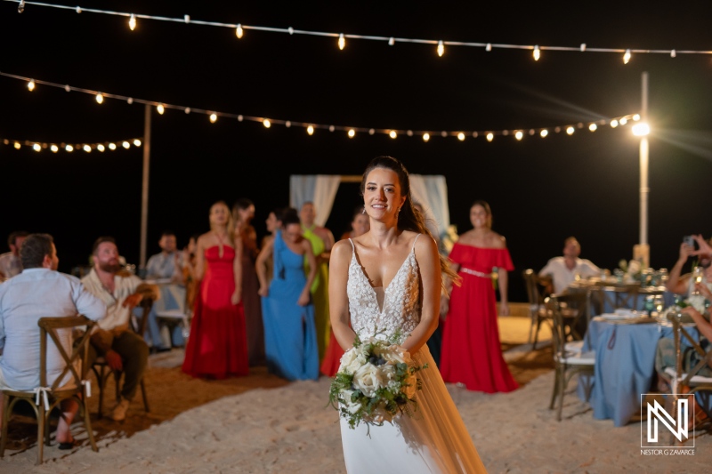 A joyful bride celebrates her wedding night on the beach, surrounded by friends and family under twinkling lights while holding a beautiful bouquet